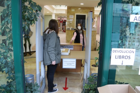 Entrega de libros a una usuaria en el mostrador habilitado a la entrada de la biblioteca