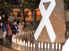 Velas junto a un lazo blanco en recuerdo a las víctimas