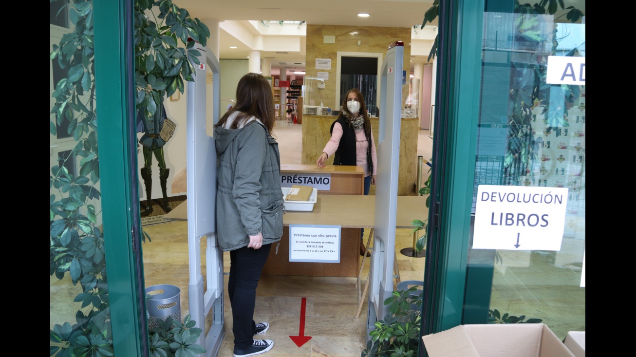 Entrega de libros a una usuaria en el mostrador habilitado a la entrada de la biblioteca